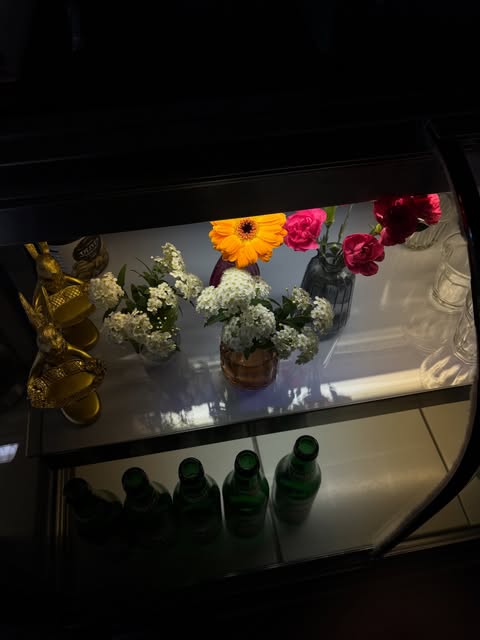 夜のショーケース。花と金色のうさぎ、緑の瓶が並ぶ